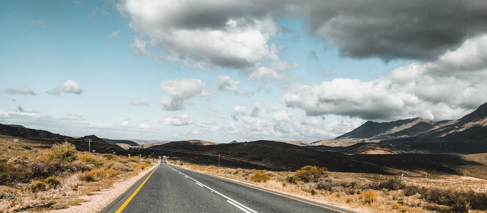 A tarred road curving through open country towards distant mountains
