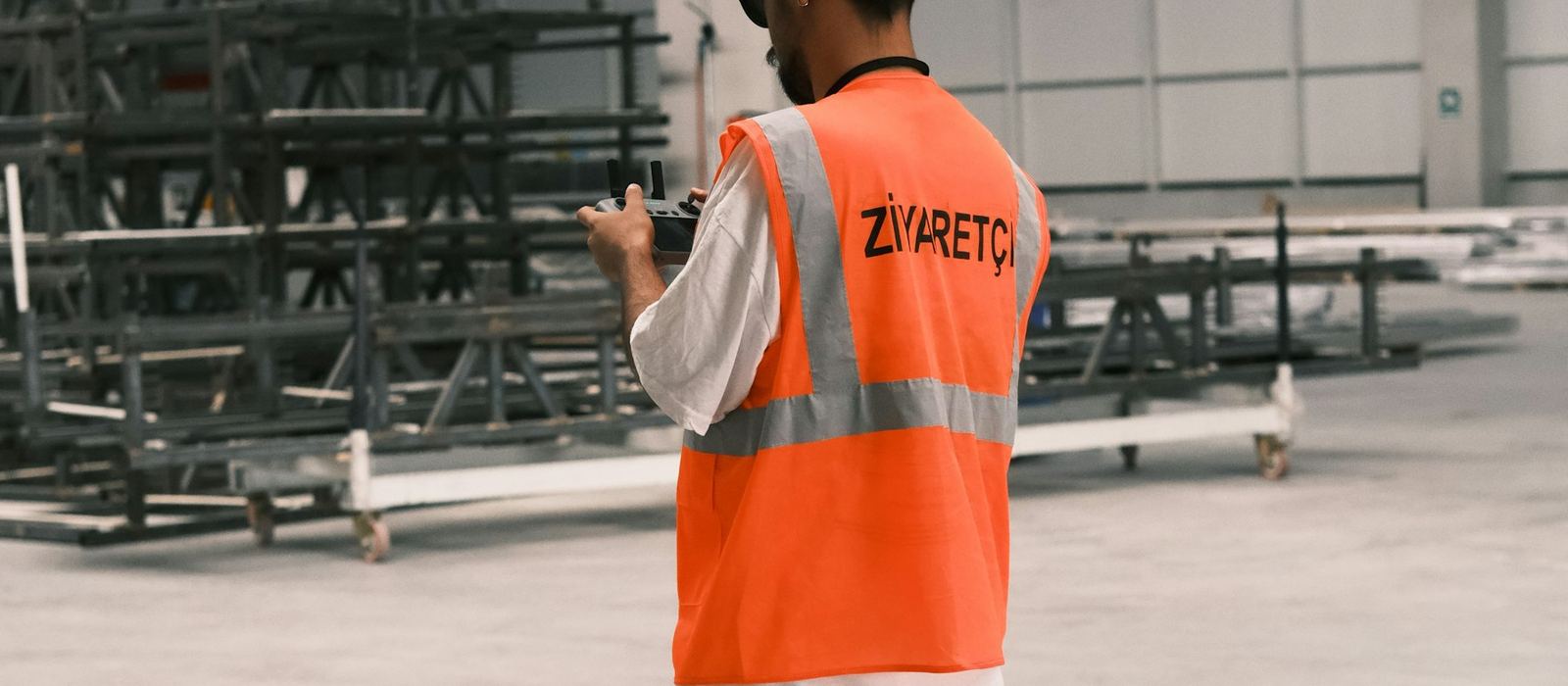 A worker in a high-visibility vest and hard hat walking through a storage facility
