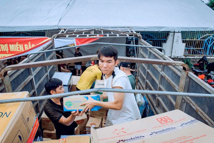 Two people loading cardboard boxes of donated goods onto a vehicle