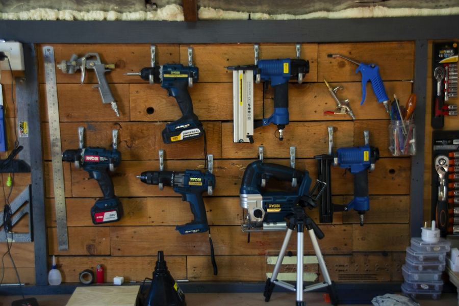 Hand tools and power tools arranged on a workshop wall